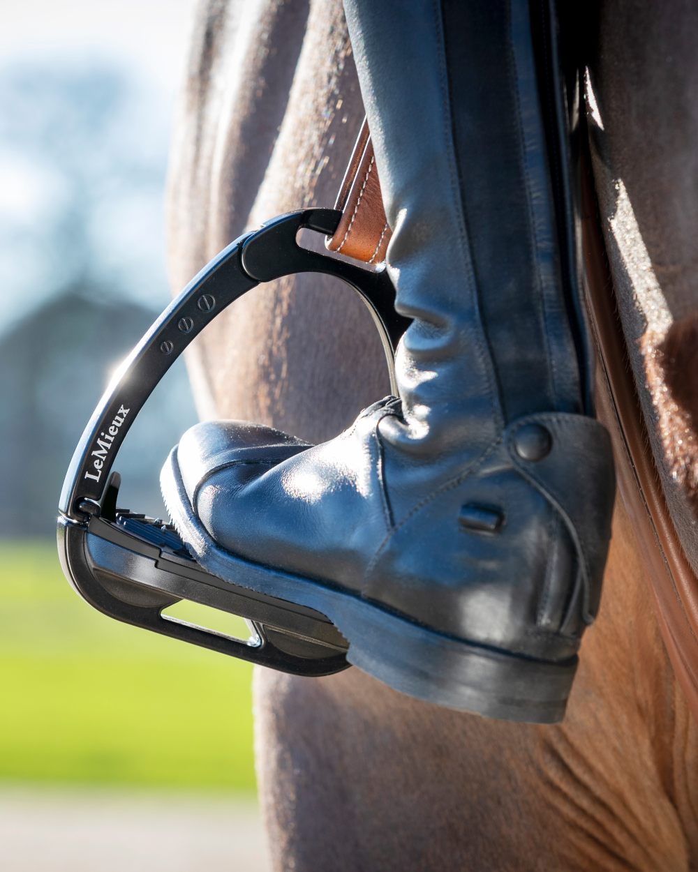 Black coloured LeMieux Vector Balance Stirrup on blurry brown background 