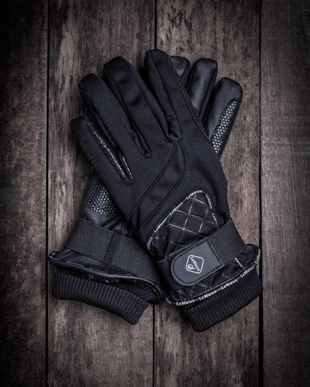 Black coloured LeMieux Waterproof Lite Gloves on wooden background 