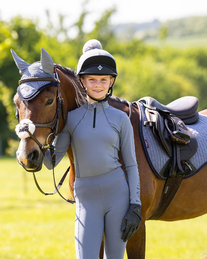 Jay Blue coloured LeMieux Young Rider Base Layer on blurry green background 