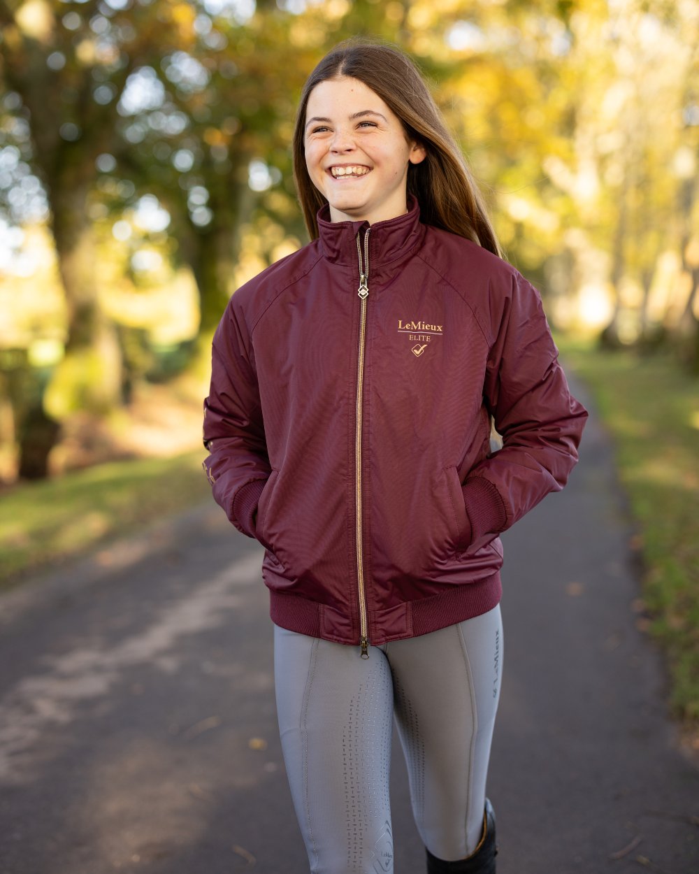 Burgundy coloured LeMieux Young Rider Elite Team Jacket with road in background 