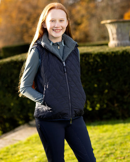 Navy Coloured LeMieux Young Rider Eloise Reversible Winter Gilet On A Outer Yard Background 