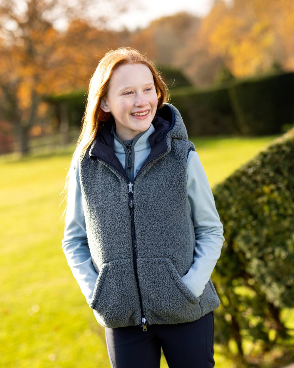 Navy Coloured LeMieux Young Rider Eloise Reversible Winter Gilet On A Outer Yard Background 