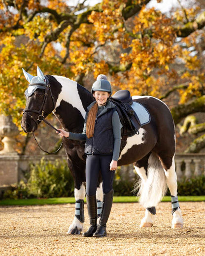 Navy Coloured LeMieux Young Rider Eloise Reversible Winter Gilet On A Outer Yard Background 