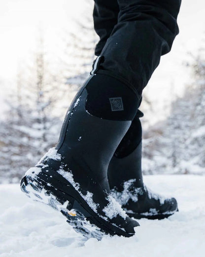 Black Coloured Muck Boots Mens Arctic Ice Vibram AG All Terrain Mid Wellingtons On A Snow Background