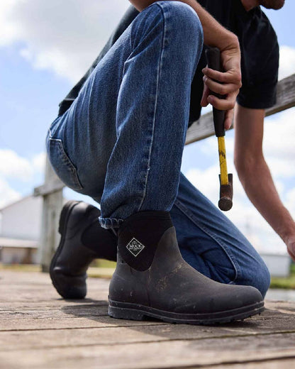 Black Coloured Muck Boots Mens Originals Excursion Ankle Boots on Outdoor Background
