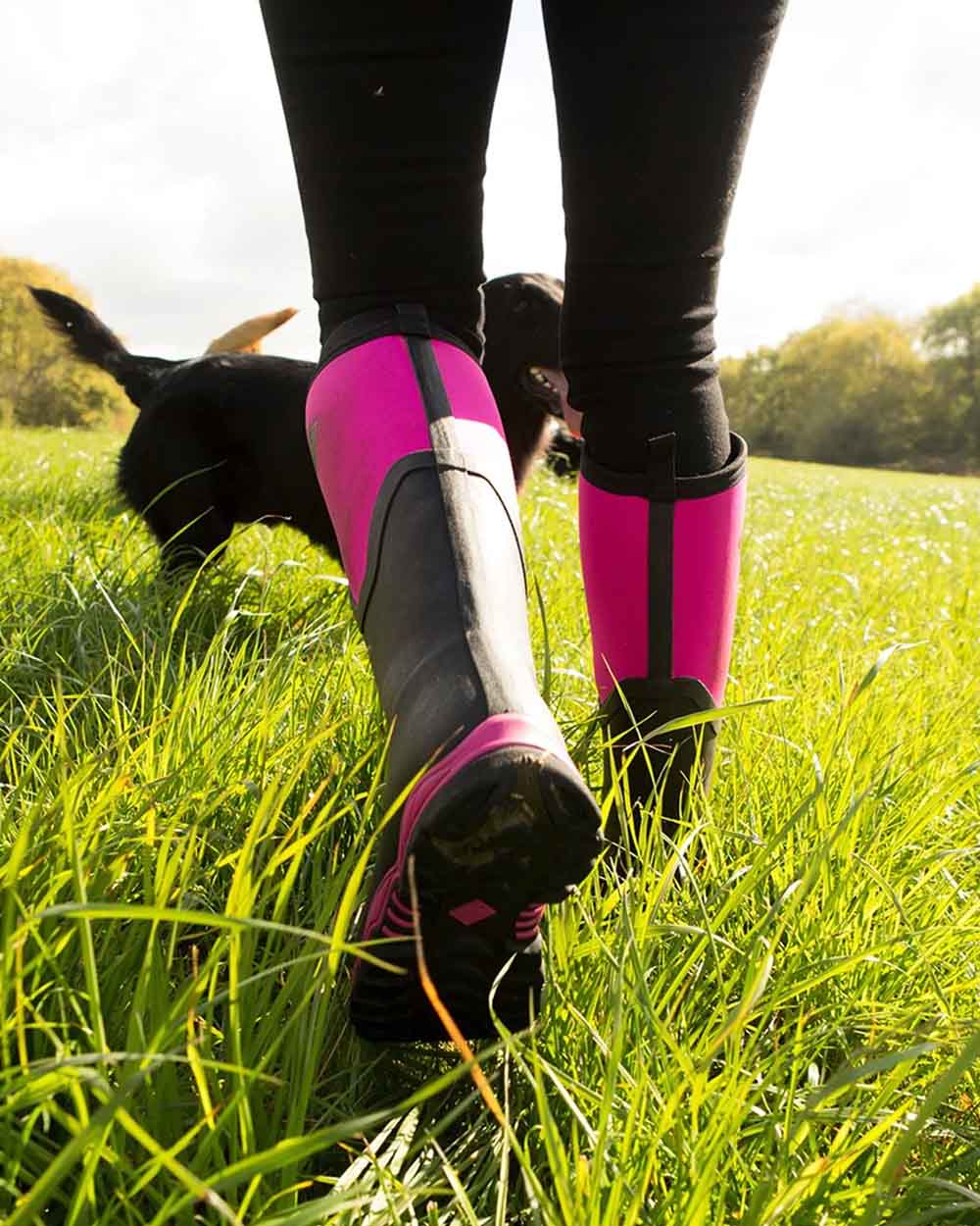Hot Pink coloured Muck Boots Womens Artic Sport II Tall Wellingtons on Grassy background 