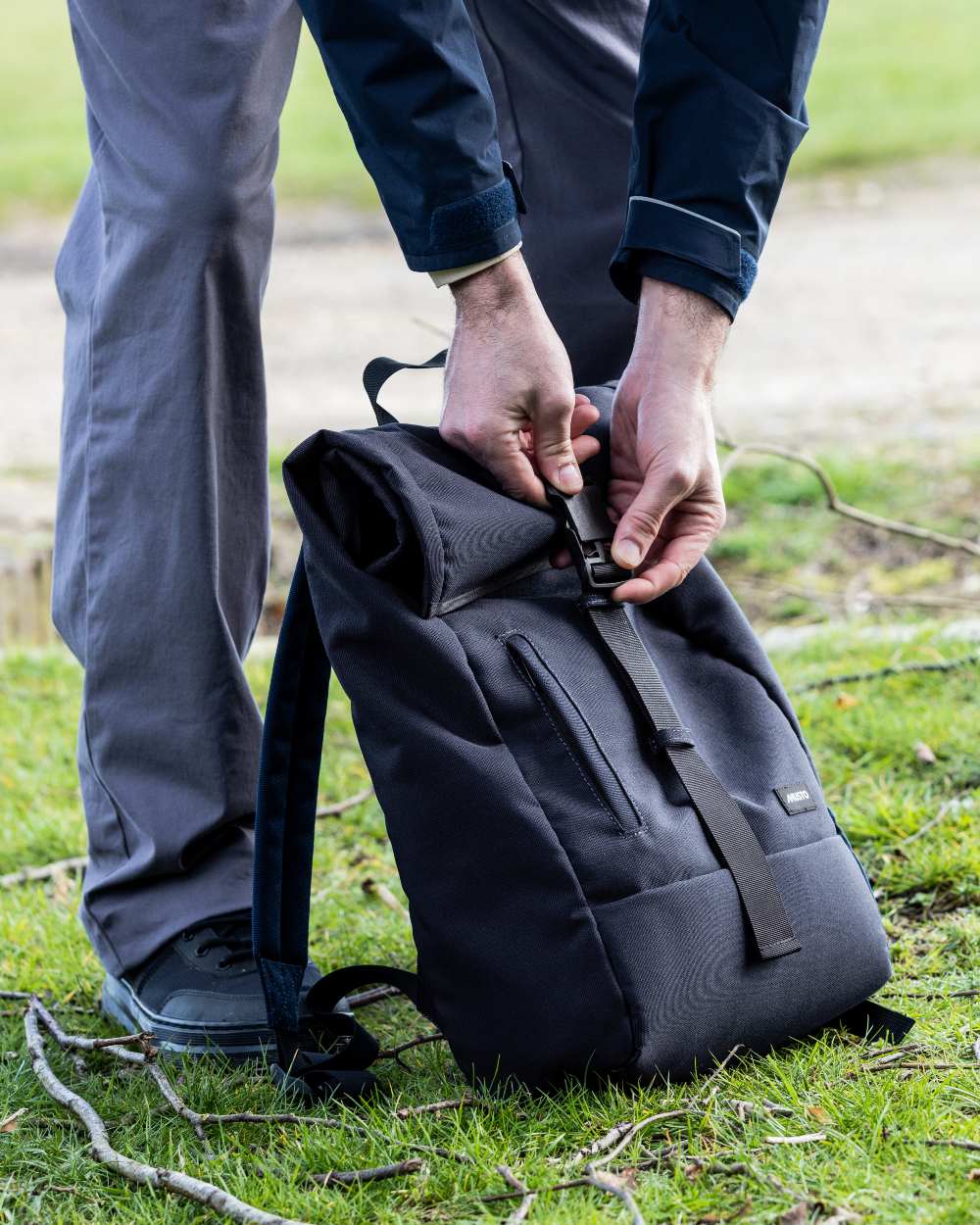 Navy Coloured Musto Canvas Roll Top Bag On A Coastal Background