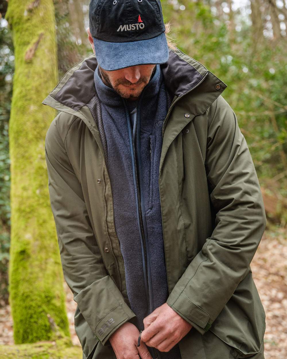 Deep Green coloured Musto Fenland Jacket 2.0 on forest background 