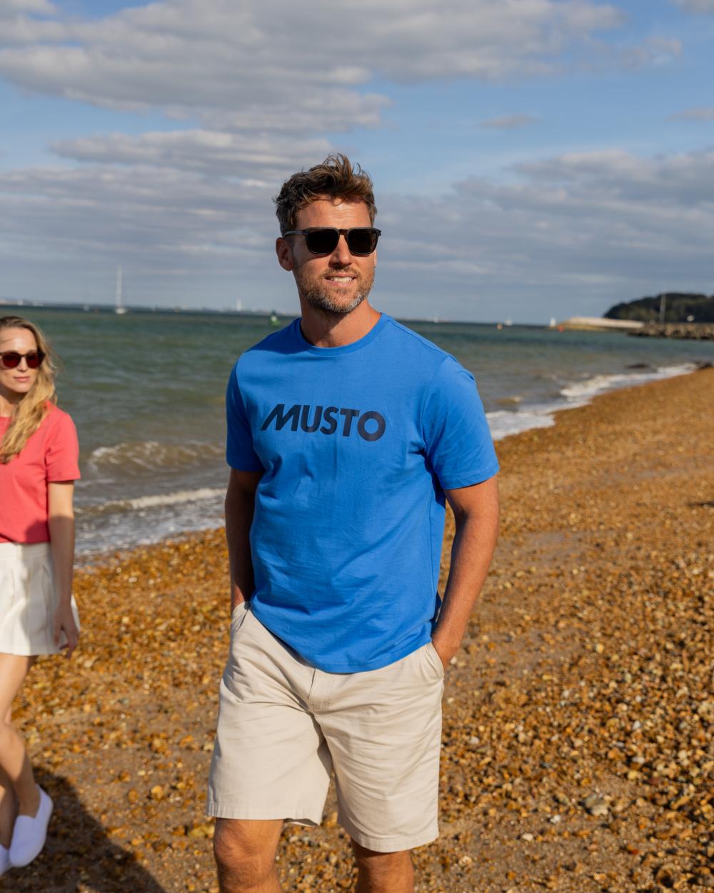 Nebulas Blue Coloured Musto Logo Cotton Tee on Beach Background
