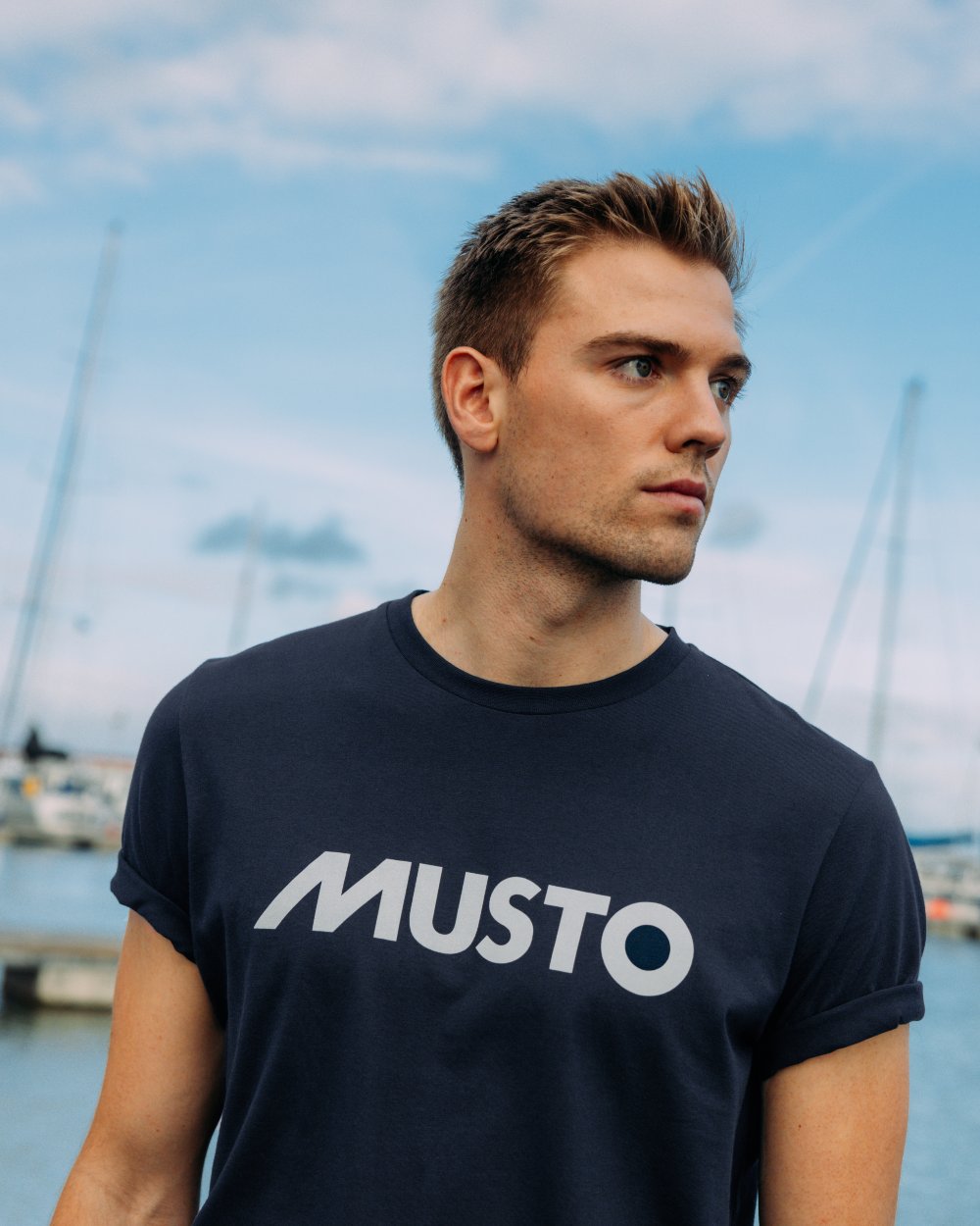 Navy Coloured Musto Logo Tee On A Sea Background 