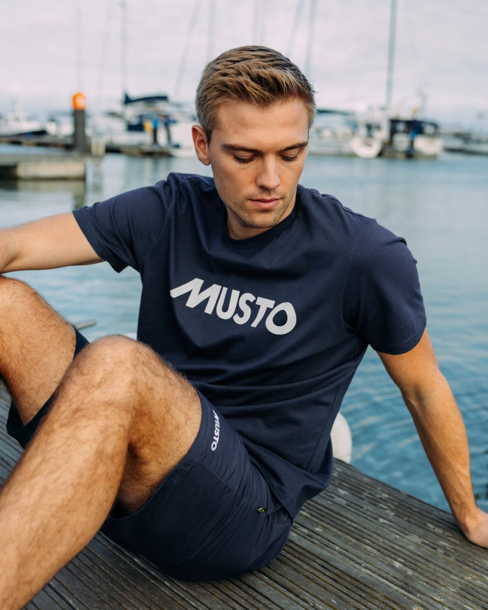Navy Coloured Musto Logo Tee On A Sea Background 