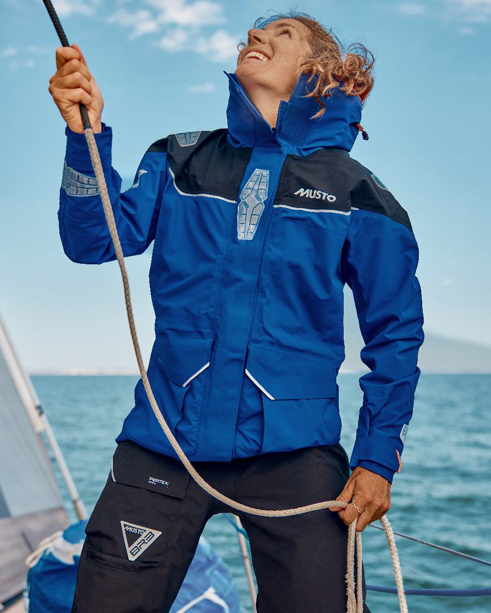 Mazarine Blue Coloured Musto Womens Br3 Pertex Offshore Jacket on sea Background
