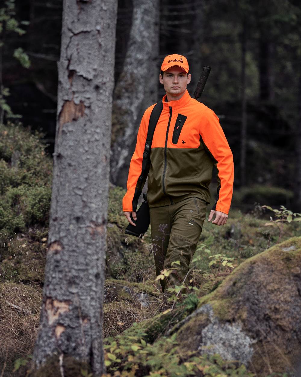 Hi-Vis Orange Coloured Seeland Force Advanced Softshell Jacket On A Forest Background