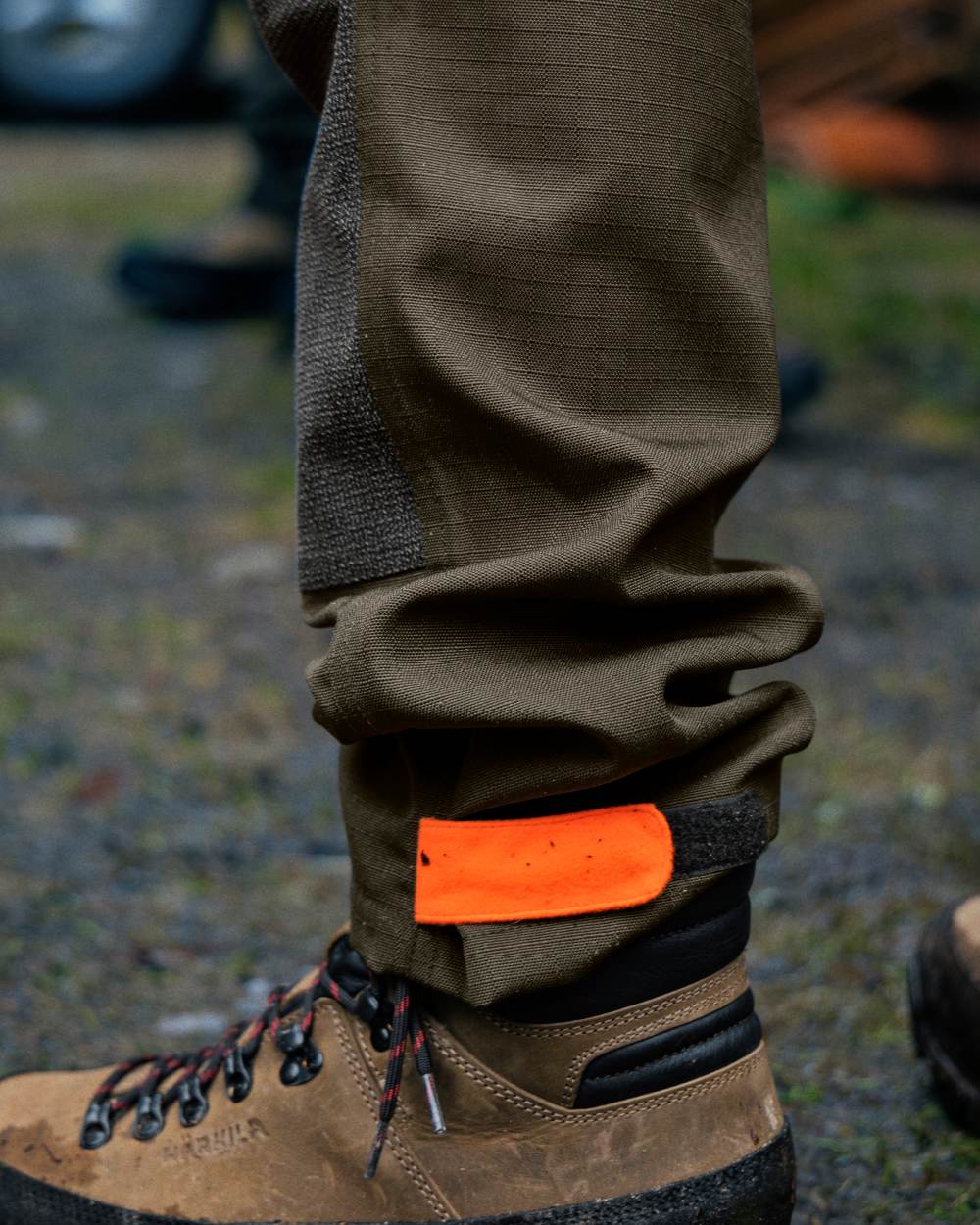 Pine Green/Hi-Vis Orange Coloured Seeland Venture Trousers On A Forest Background