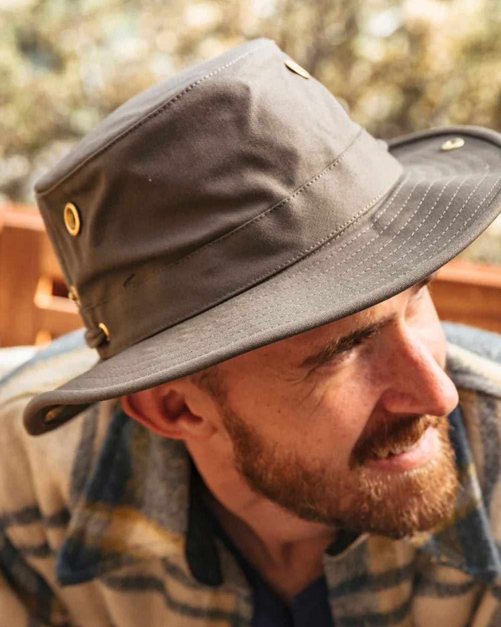 Olive coloured Tilley Classic T3 Cotton Hat on Blurred Forest background 