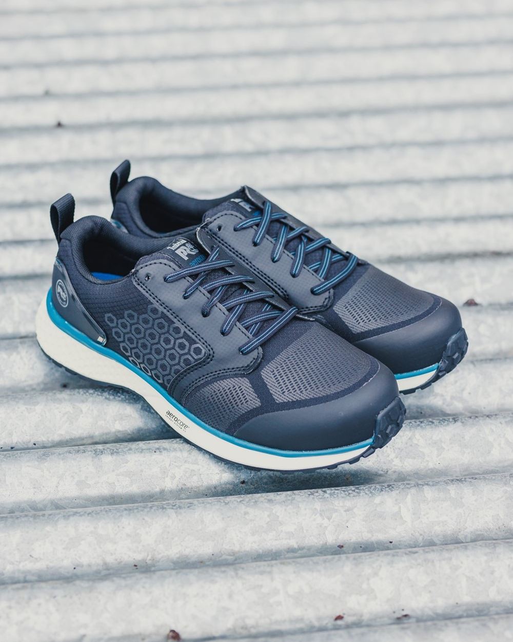 Black/Blue coloured Timberland Pro Reaxion Composite Safety Trainers on grey roof background 