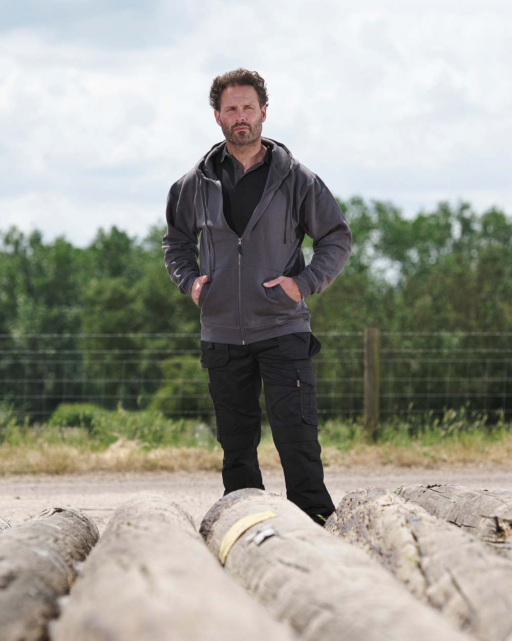 Grey coloured TuffStuff Pro Work Hoodie on Fence line background 