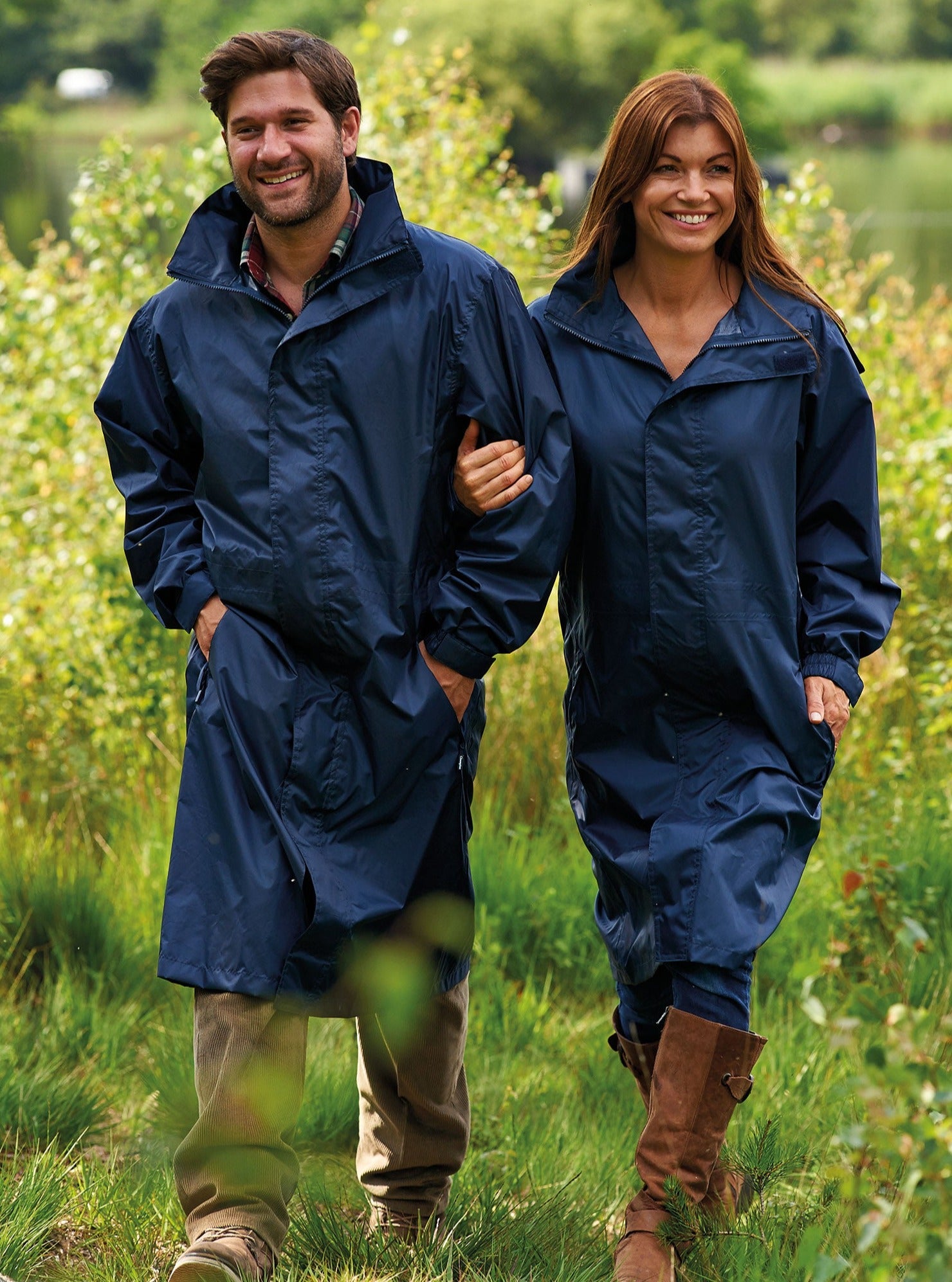Man and woman wearing Champion Storm long waterproof coat  in navy with woods in background.