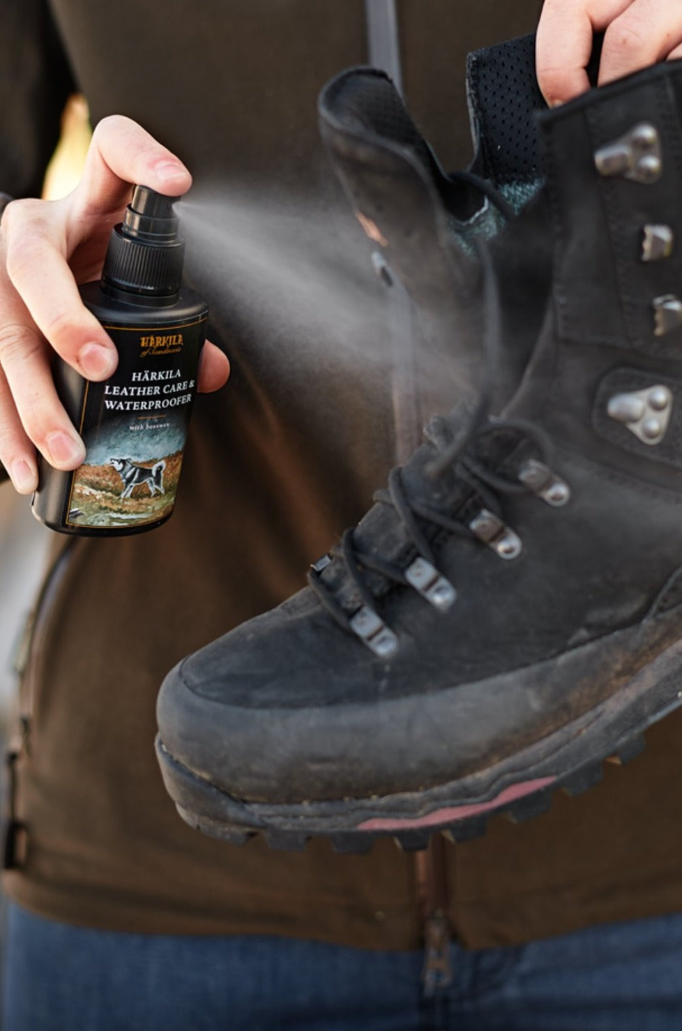 Harkila Waterproofing Leather Care Neutral showing someone close up squrting the product onto some boots